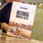 Okładka książki a na niej napis: Leszek Migrała, Historia Nowego Sącza, z tyłu zarys kobiecej postaci siedzącej na kanapie.