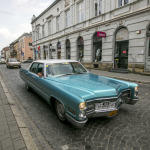 Jasnobłękitny samochód typu Cadillac, w tle zabytkowe kamienice.