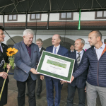 Kilkoro osób na scenie, kobieta w mundurze trzyma kwiat słonecznika, jeden z mężczyzn trzyma plakat z napisem.