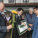 Zgromadzeni na scenie ludzie kobieta w mundurze gratuluje mężczyźnie.