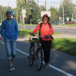 Kobieta trzymająca rower obok mężczyzna, oboje stoją na ścieżce rowerowej.