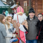 Dwie dziewczyny obok mężczyzny przebranego za św. Mikołaja, obok mężczyzna i dziewczynka przebrana za diabełka.