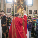 Ksiądz święci palmy trzymane przez ludzi w kościele.