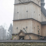 Drewniany kościół, przed nim wielkanocne palmy.