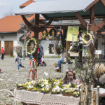 Stroiki wielkanocne na stoisku, z tyłu ludzie i budynki.