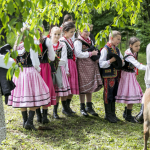 Dzieci w strojach regionalnych, obok dziewczynka na kucyku.