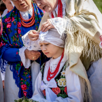 Kobieta w góralskim stroju ubiera dziewczynce czepiec na głowę, obok inne kobiety.