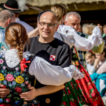 Górale tańczący na scenie z osobami z publiczności.