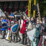 Grupa osób w strojach historycznych zebrana na kościelnym dziecińcu.