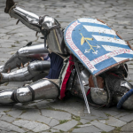 Mężczyźni przebrani za rycerzy podczas pojedynku, leżący na ziemi.