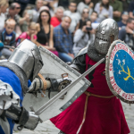 Mężczyźni przebrani za rycerzy podczas pojedynku, z tyłu publiczność.