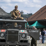 Mężczyzna w mundurze siedzący na dachu wojskowego samochodu