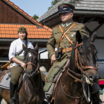 Siedzący na koniu mężczyzna w wojskowym mundurze, za nim kobieta na koniu.