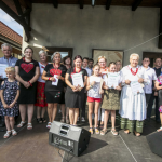 Grupa ludzi stojąca na scenie i trzymająca dyplomy.