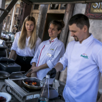 Dwie kobiety i mężczyzna stojący za stołem ze sprzętem kuchennym.