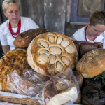 Dwie kobiety siedzące za stołem z pieczywem.