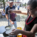 Kobieta nalewająca chochelką zupę do miski, przed nią mężczyzna.