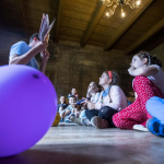 Mężczyzna pokazuje dzieciom książkę, obok balon.