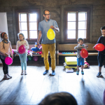 Mężczyzna trzymający balon, obok niego dzieci z balonami.