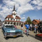 Jasnoniebieski samochód typu cadillac, naokoło ludzie i budynki.