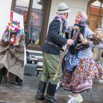 Fragment przedstawienia: trzy osoby w kolorowych przebraniach. W tle chłopiec i mężczyzna grają na flecie.