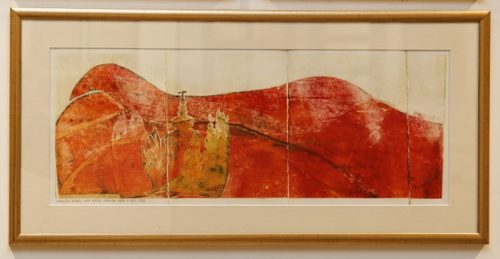 Pomarańczowy obraz w ramie, przedstawiający pola, świątynię i drzewa.