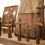 Drewniana rzeźba i krzyż znajdujący się w sali muzealnej.