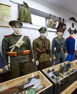 Manekiny ubrane w żołnierskie mundury, na ścianach wiszą plecaki i obrazy, w skrzynkach wojskowe akcesoria.