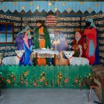 Inscenizacja pokłonu trzech króli w izbie. Postacie z drewna, malowane. W tle malowana w kwiaty ścianka.