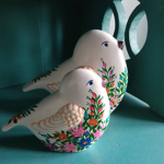 Dwa ceramiczne ptaszki, ozdobione malowanymi kwiatami.