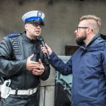 Mężczyzna rozmawia z policjantem na scenie.