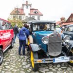 Zabytkowe samochody na płycie rynku miasteczka galicyjskiego.