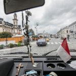 Wnętrze zabytkowego autobusu, w tle budynek ratusza.