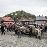 Ludzie stojący na rynku miasteczka galicyjskiego, zabytkowe samochody.