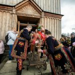 Mężczyźni ubrani po lachowsku ciągną wózek z figurką Jezusa na osiołku