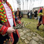 Mężczyźni w strojach regionalnych niosą gałązki wierzby